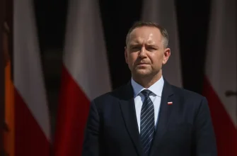 Президент Польши Кароль Навроцкий стоит возле польских флагов