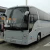 Светло-серый туристический автобус марки "МАЗ", принадлежащий ГП "Минсктранс" стоит на стоянке недалеко от стеклянного здания автовокзала.