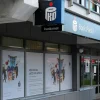 Внешний вид отделения PKO Bank Polski с банкоматом и вывеской. На окнах отделения размещены тематические рекламные плакаты.