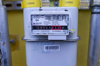 Крупный план бытового газового счетчика G4 с цифровым дисплеем, показывающим текущее потребление газа в кубических метрах, на фоне желтой стены.