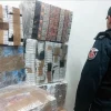 Сотрудник Таможенно-налоговой службы Польши стоит рядом с огромными штабелями изъятых нелегальных сигарет беларуского производства, упакованных в пленку.