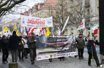 Участники манифестации в Белостоке в защиту Государственных лесов и лесопромышленного сектора несут большой транспарант с лозунгами о поддержке лесов и флаг профсоюза "Солидарность".