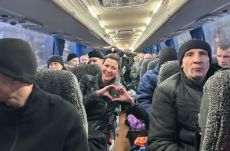 Мария Колесникова, одна из освобожденных политических заключенных, улыбается и показывает руками жест "сердце" среди других пассажиров в салоне автобуса, направляющегося из Беларуси.