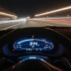 Вид из салона спортивного автомобиля на ночную дорогу, где приборная панель показывает скорость 314 км/ч. Яркие линии света на лобовом стекле создают эффект движения и скорости.