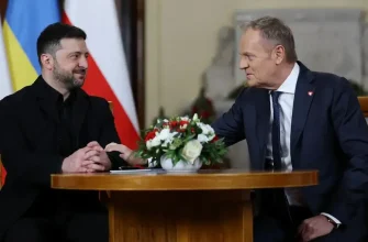 Владимир Зеленский и Дональд Туск сидят за круглым столом с цветами.